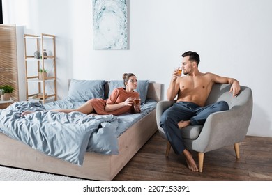 Young Couple Looking At Each Other While Drinking Tea In Modern Bedroom