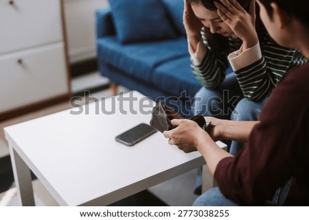 Young couple looking at an empty wallet, feeling stressed and anxious about financial problems and economic difficulties