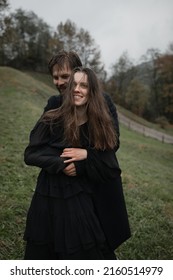 A young couple in love in black coats walks in the countryside in the rain. Autumn gloomy mood. Cinematic image