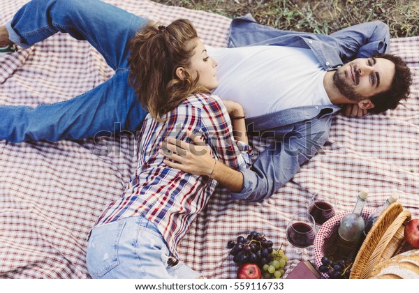 Young couple in love doing a picnic outdoors in\
Tuscany wine country