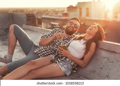 Young Couple In Love Drinking A Pineapple Cocktail And Having Fun At Rooftop Party In Sunset. Focus On The Guy