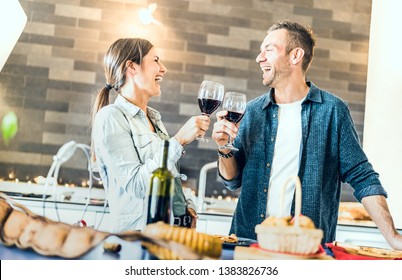 Young Couple In Love Drinking Red Wine In House Kitchen - Happy Millenial People At Home Enjoying Aperitif Time Cheering Together At Jubilee Anniversary - Genuine Youth Concept On Bright Indoor Filter