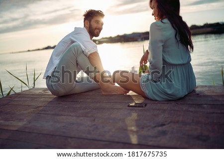 Young couple in love enjoying the sunset on the lake on a beautiful weather