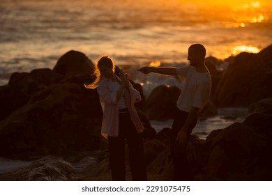 A young couple in love fooling around on the rocky oceanfront during an amazing sunset.  - Powered by Shutterstock