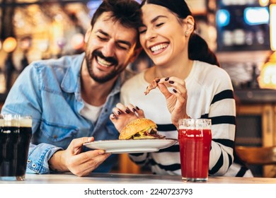 Young couple in love having fun spending leisure time together at restaurant, eating burgers and drinking beer - Powered by Shutterstock