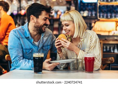 Young couple in love having fun spending leisure time together at restaurant, eating burgers and drinking beer - Powered by Shutterstock