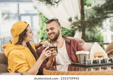 Young couple in love having fun spending leisure time together at restaurant, eating burgers and french fries, drinking cola  - Shutterstock ID 2315759943