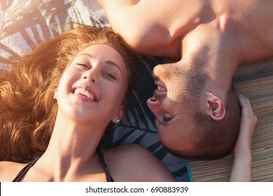 Young couple in love having fun on a beach, laying on towels, view from above  - Shutterstock ID 690883939