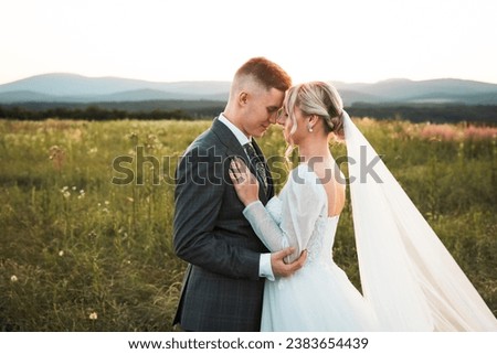  young couple in love holding each other, bride and groom during wedding photoshoot, shot of newlyweds in the middle of a sun-covered field, beautiful bride and stylish groom, love is here,models