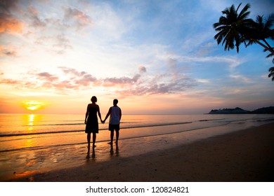 A young couple in love holding hands at sunset at the seaside