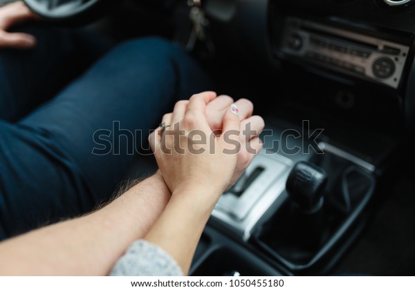 A young\
couple in love holding hands, holding on the shift lever going into\
the road trip. A man and a girl go together by car. Young couple\
holding hands in car. Wedding\
rings.