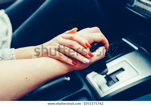 A young couple in love holding hands, holding on\
the shift lever going into the road trip. A man and a girl go\
together by car. Young couple holding hands in car. Wedding rings.\
Stylish Toned photo