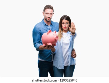 Young couple in love holding piggy bank over isolated background with open hand doing stop sign with serious and confident expression, defense gesture - Shutterstock ID 1293625948