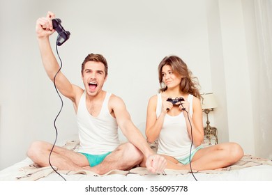 Young couple in love at home playing games joysticks and he winning