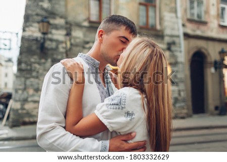 Young couple in love kissing in old Lviv city wearing traditional ukrainian shirts. Man and woman hug