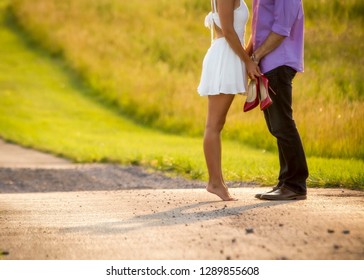 young couple in love, lovers kissing, barefoot girl on tip toes, barefoot walking, afternoon light, dirt road and field landscape