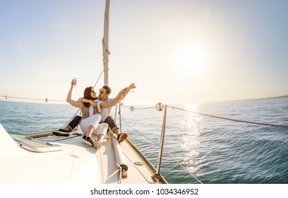 Young couple in love on sail boat with champagne at sunset - Happy people lifestyle on exclusive luxury concept  - Soft backlight focus on warm afternoon sunshine filter - Fisheye lens distortion