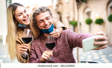 Young Couple In Love With Open Face Mask Taking Selfie At Outside Wine Bar - Happy Millennial Lovers Enjoying Lunch Together At Restaurant Patio - New Normal Lifestyle Concept On Bright Pastel Filter