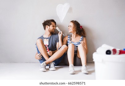 Young Couple In Love Painting Walls In Their New Home.