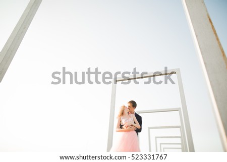 Young couple in love posing on roof with perfect city view holding hands and hugging . Beautiful sunset