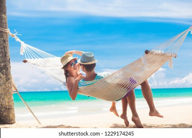 Young couple in love relaxing in a hammock by the beach