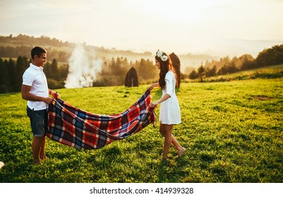 Young couple in love resting on peak of mountain in summer. Couple spreading a blanket for picnic - Powered by Shutterstock