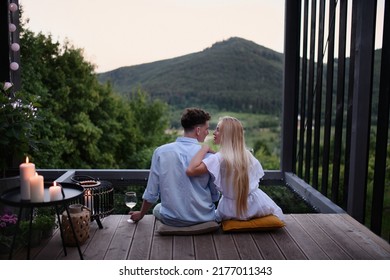 Young couple in love resting outdoors on terrace of tiny house in woods with view in evening, weekend away in tiny house in countryside, sustainable living. - Powered by Shutterstock