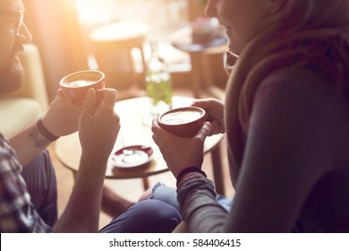 Young couple in love sitting in a cafe, drinking coffee, having a conversation and enjoying the time spent with each other. Selective focus - Powered by Shutterstock