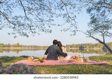 Young couple in love sitting on blanket with picnic basket and embracing to watching lake view. - Powered by Shutterstock