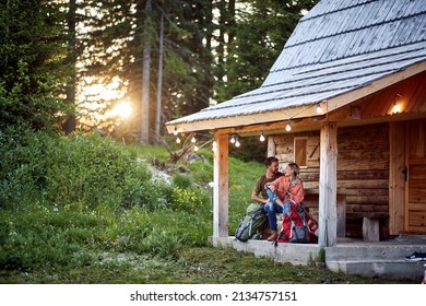 A young couple in love spending time together at the cottage porch in the forest on a beautiful day. Vacation, nature, cottage, relationship - Powered by Shutterstock