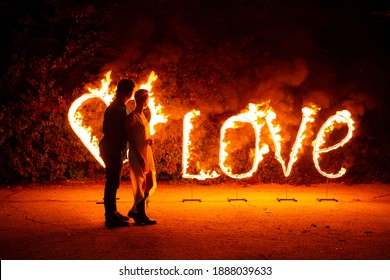 Young Couple In Love Standing Near Burning Fire Letters Love And Heart