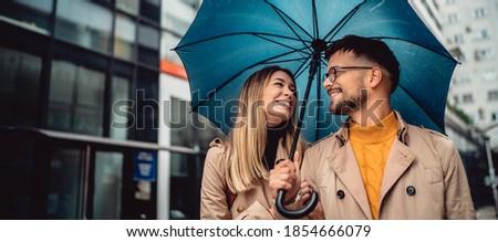 Young couple in love standing in the rain under an umbrella
