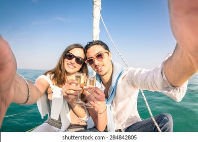 Young Couple In Love Taking Selfie On Sailing Boat Cheering With Champagne Wine - Happy Jubilee Party Cruise Travel On Luxury Sailboat With Boyfriend And Girlfriend - Bright Sunny Afternoon Color Tone