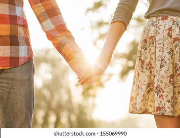 Young couple in love walking in the autumn park holding hands looking in the sunset  - Powered by Shutterstock