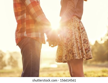 Young Couple In Love Walking In The Autumn Park Holding Hands Looking In The Sunset