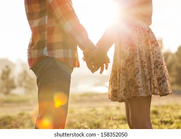 Young couple in love walking in the autumn park holding hands looking in the sunset - Shutterstock ID 158352050