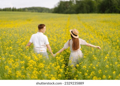 Young couple in love walks through a rapeseed field. Happy men and women in style enjoy the time spent together. The concept of love, test, relationship. - Powered by Shutterstock