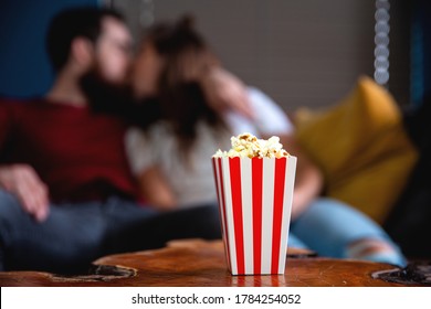 A young couple in love watching television at night romantic date night lying on the couch eating popcorn happy dating