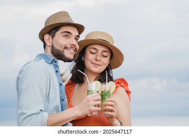 Young Couple Of Lovers Having Fun On First Date Drinking Cocktails At Bar Restaurant With Sky On Background - Focus On Girl Face