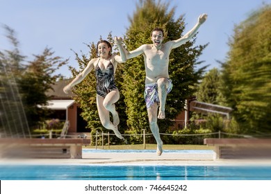 young couple of lovers jumping in the swimming pool. Concept of beautiful people having fun in summertime