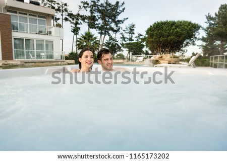 Young couple in a luxury hotel inside a hot-tub in a rainy day 
