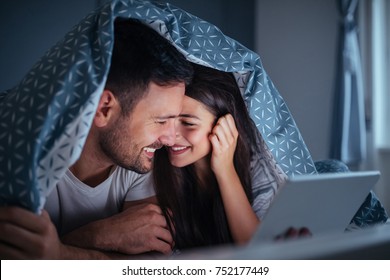 Young couple lying in bed at night , holding a tablet - Powered by Shutterstock