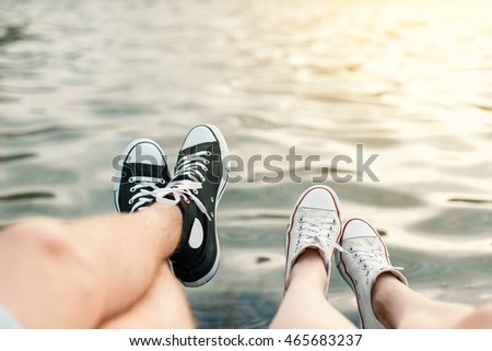 Young couple lying on the beach. Legs with sneakers near water