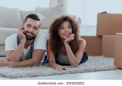 Young couple lying on the rug on the background of a new apartment - Shutterstock ID 1091033051
