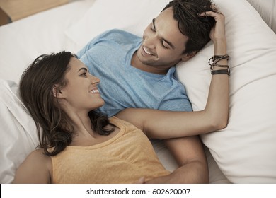 A young couple lying on a sofa gazing at each other, a man and woman, boyfriend and girlfriend