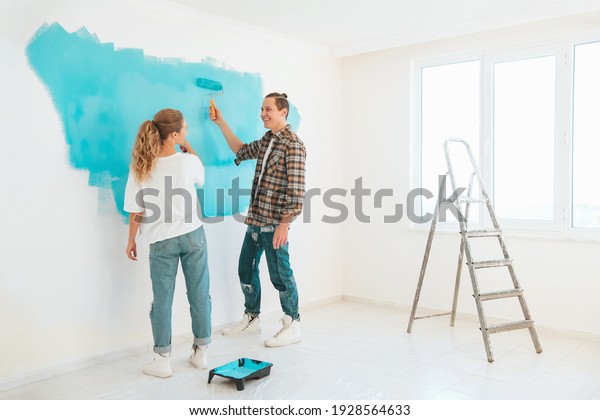 Young couple makes\
repairs in apartment and paint walls in blue color. Family\
apartment renovation\
concept