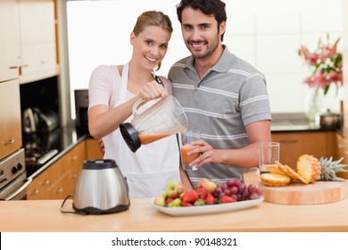 Young couple making fruits juice in their kitchen - Powered by Shutterstock