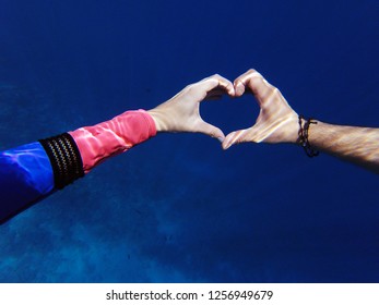 Young Couple Making Heart Shape With Their Hands Underwater While Snorkeling Or Swimming On Vacation On Tropical Island Concept