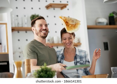 Young couple making pancakes at  home. Loving couple having fun while cooking.