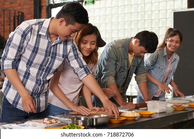 Young Couple Making Pizza At Culinary Workshop